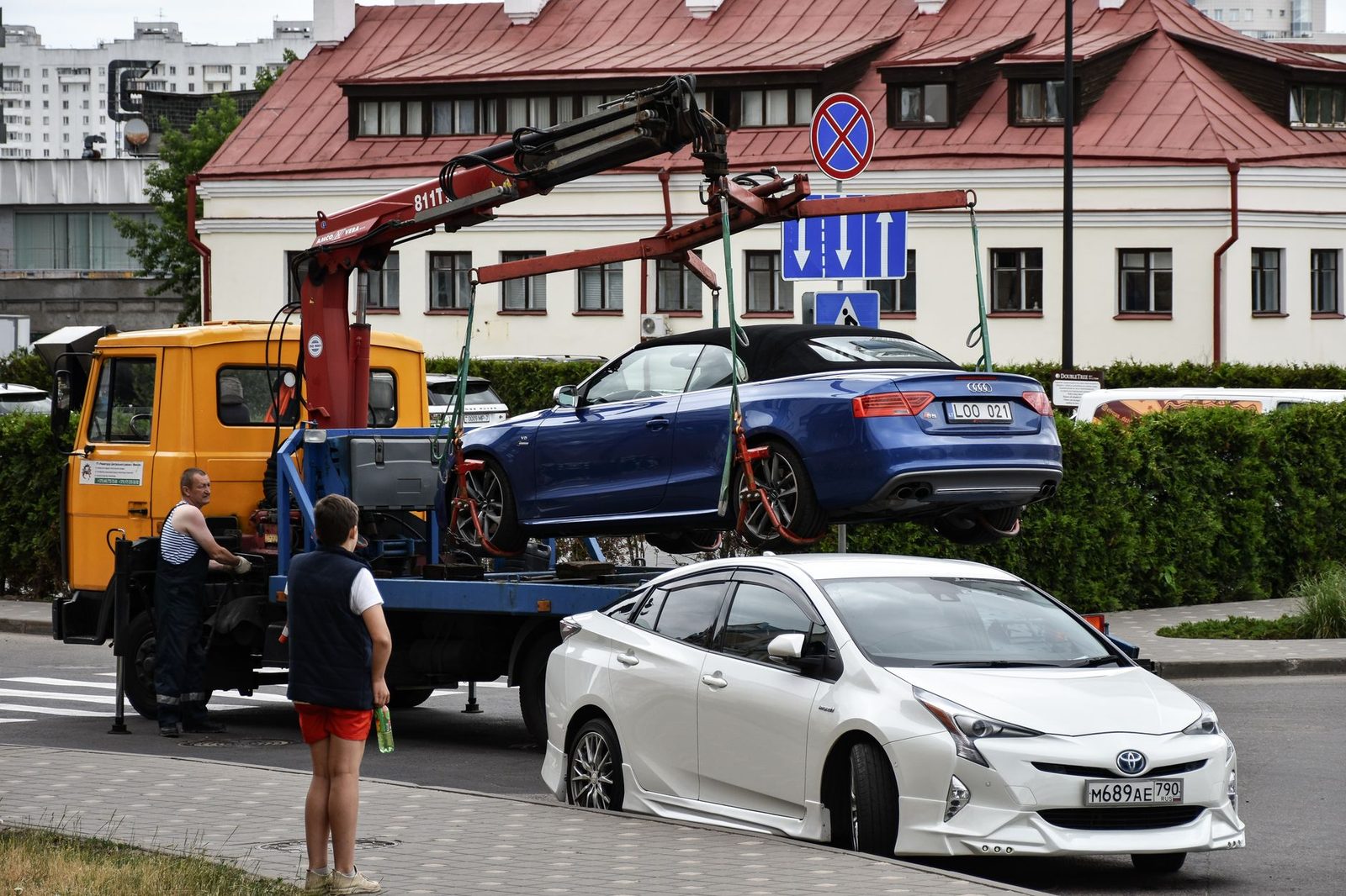 Un Audi descapotable azul es remolcado por una concurrida calle de la ciudad.