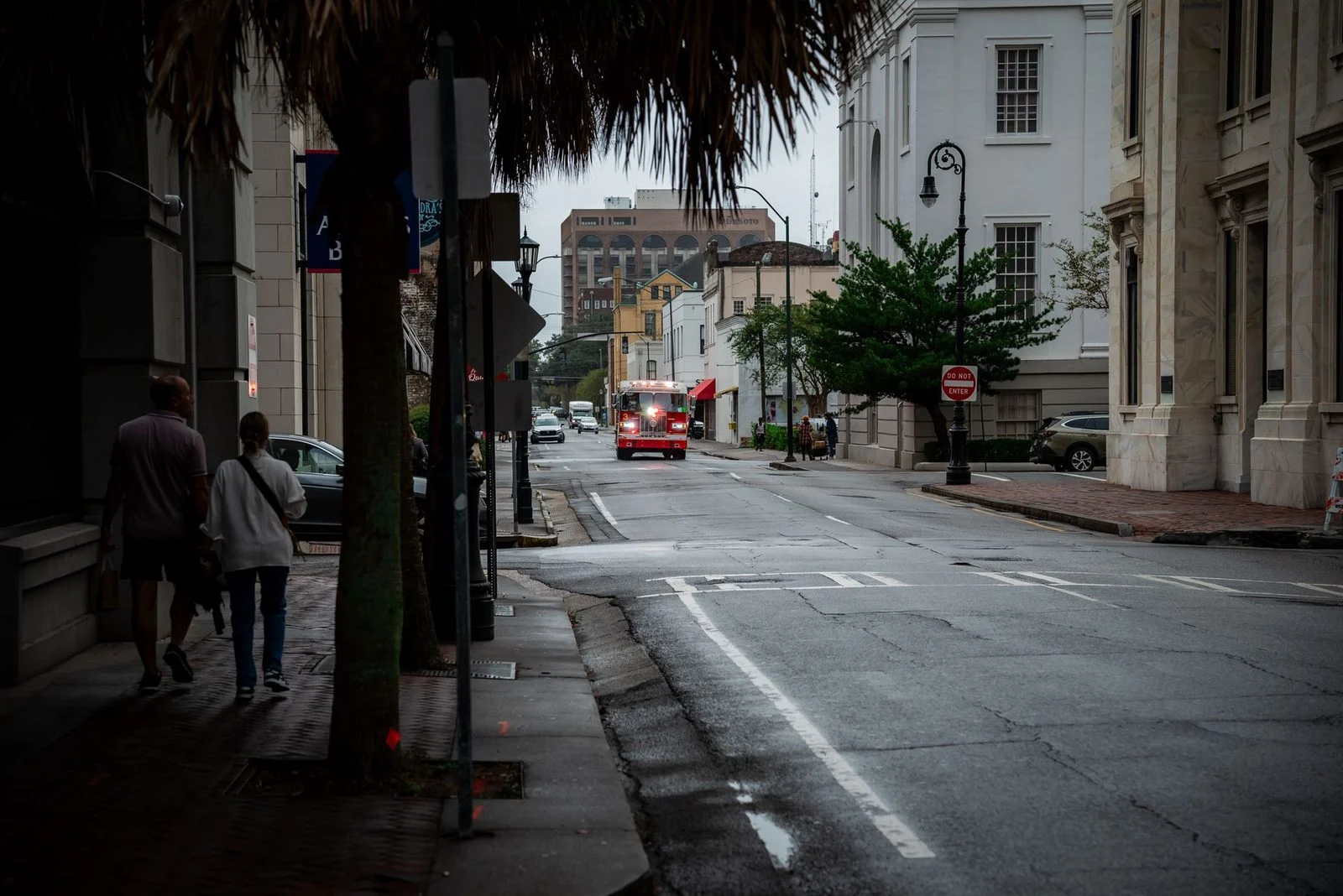 A red fire truck with lights on responds to an emergency on a street in Savannah, Georgia.