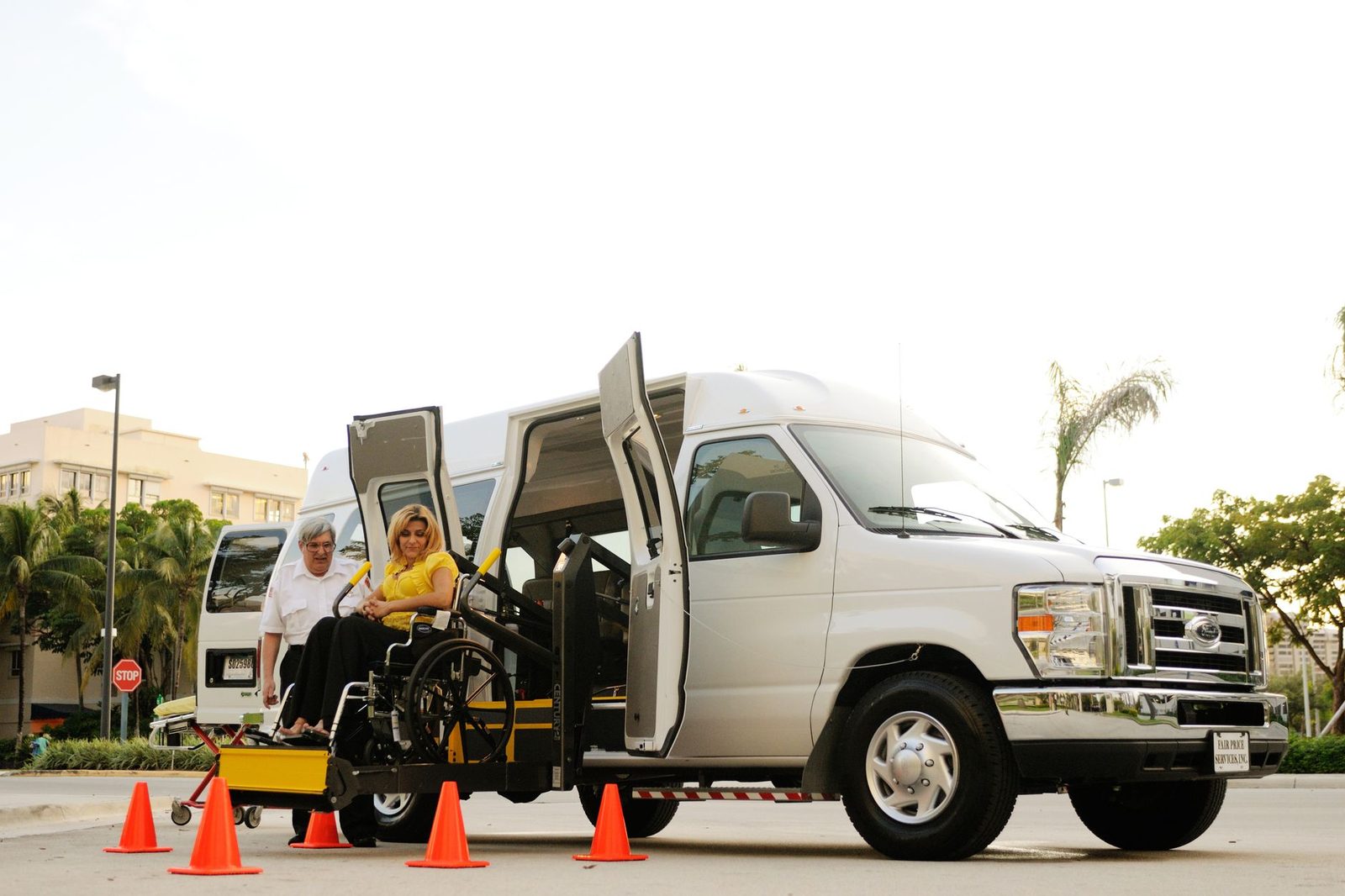 Una mujer en silla de ruedas sube a una furgoneta adaptada mediante una plataforma elevadora, con la ayuda de un conductor.