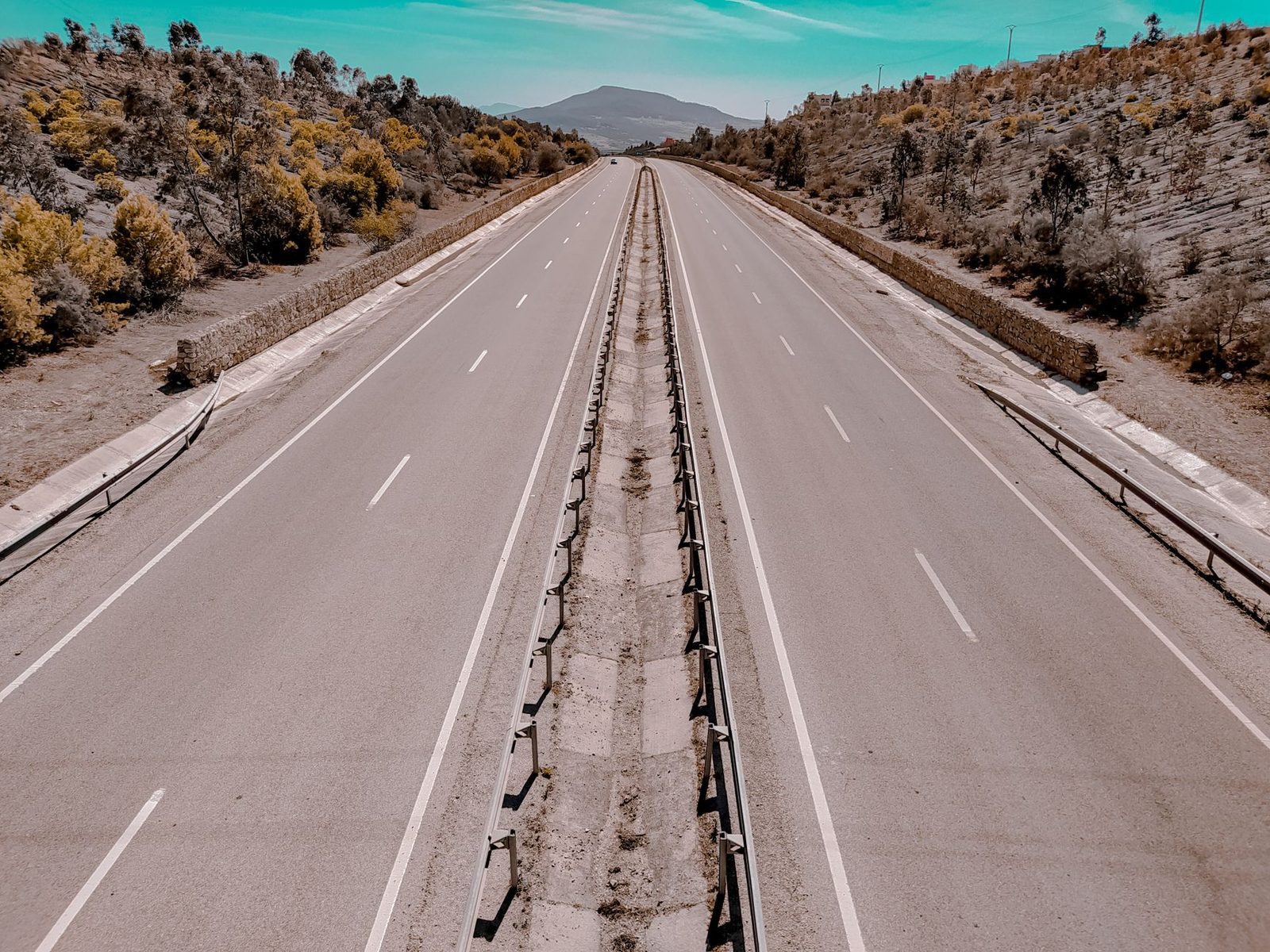 Aerial view of an empty highway winding through autumn trees.