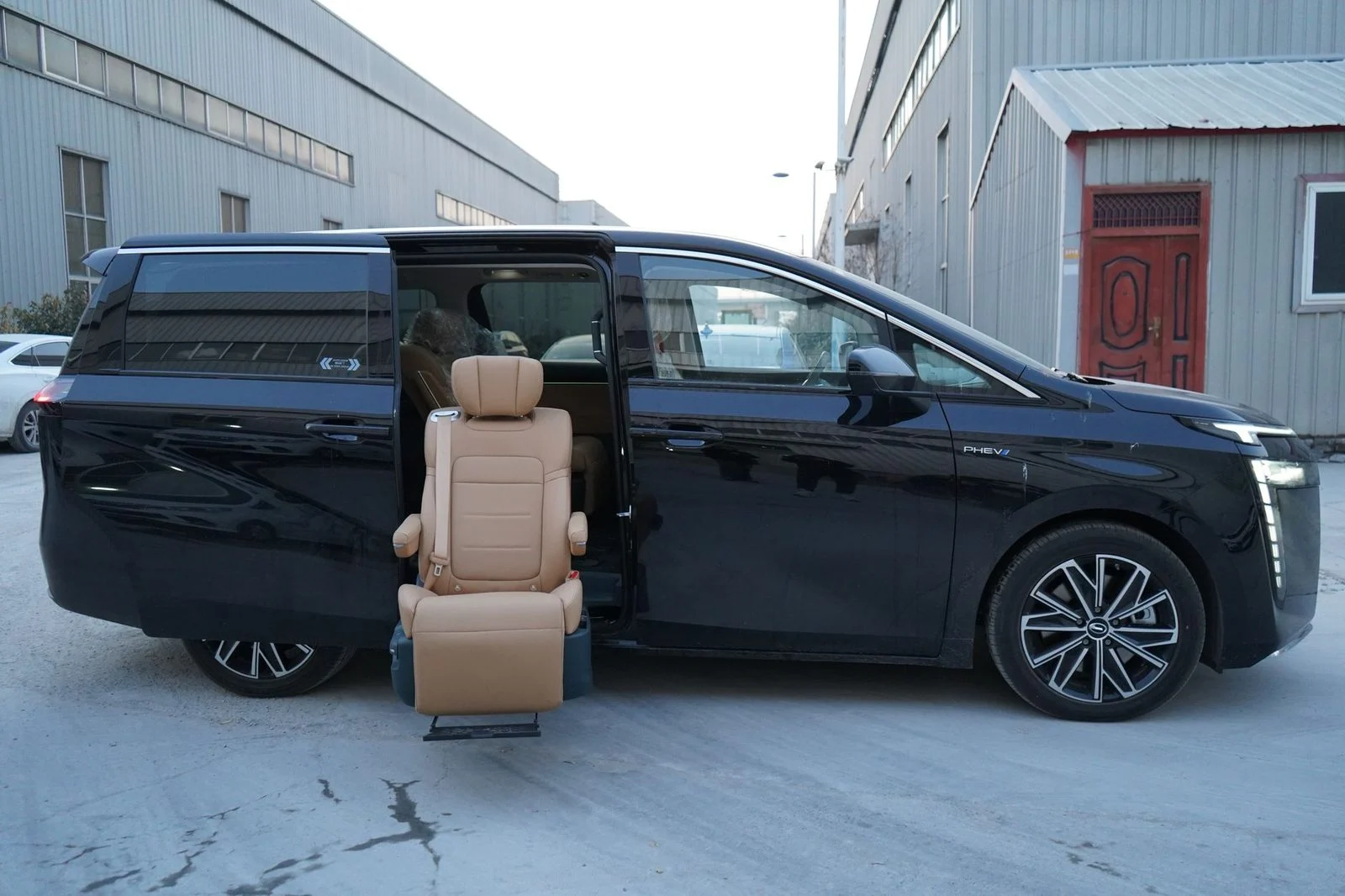 Minivan negra estacionada al aire libre con la puerta lateral abierta, mostrando un asiento accesible, en un día frío de invierno.