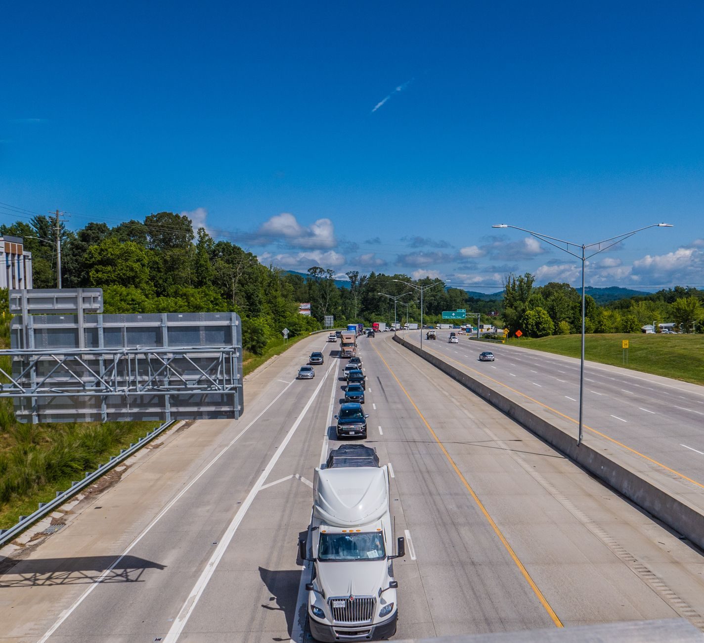 Camiones y automóviles circulando por una autopista bajo un cielo azul despejado durante el día.