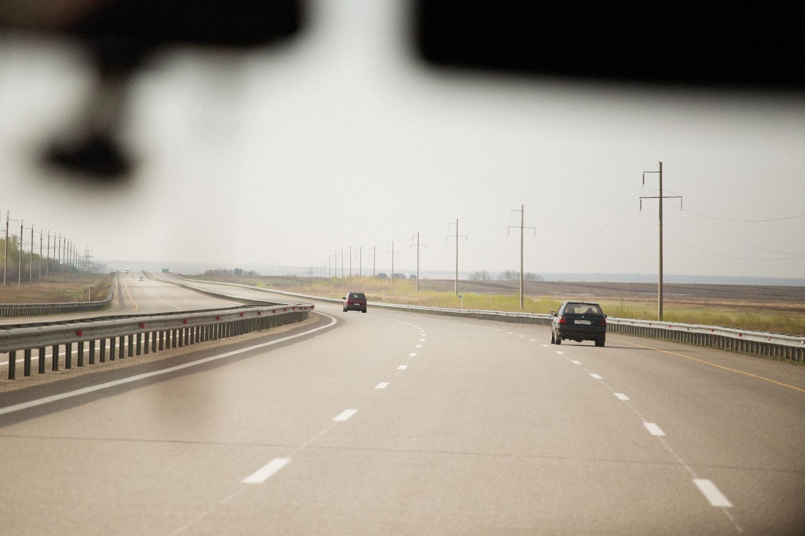 Cars travel along a wide highway, with utility poles stretching into the distance.