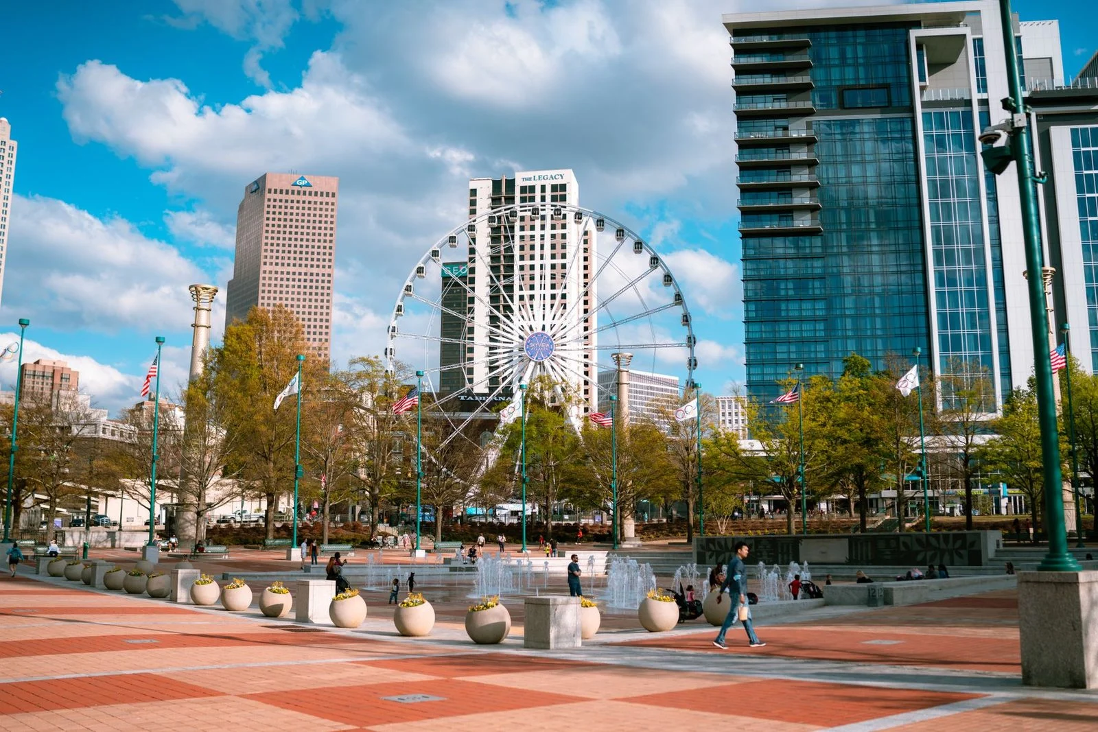 Day view of Centennial Olympic Park in Atlanta, with skyscrapers and a Ferris wheel under a clear sky.