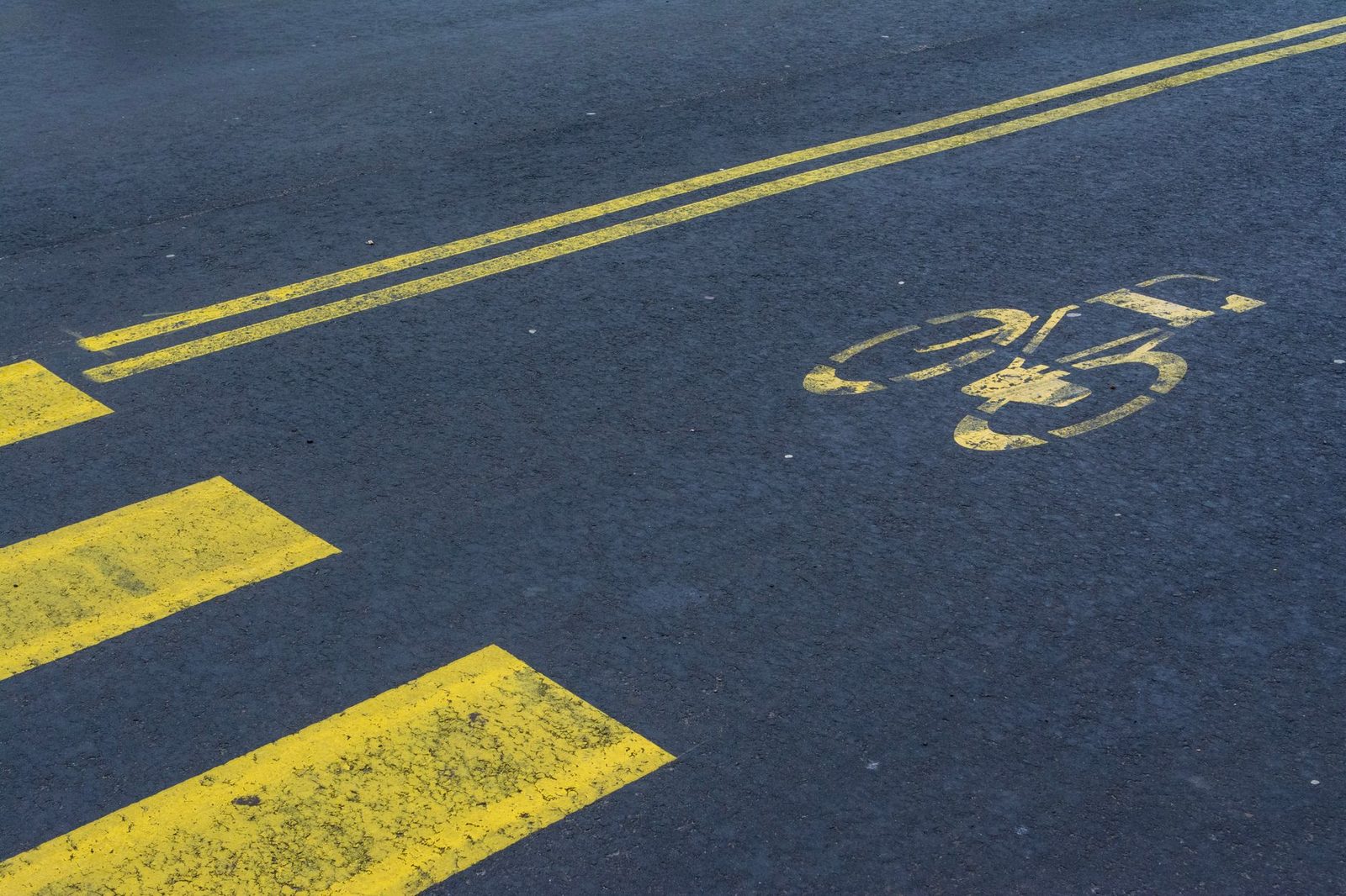 Empty asphalt road with a yellow-painted bike lane marked by a bicycle symbol and a zebra crosswalk.