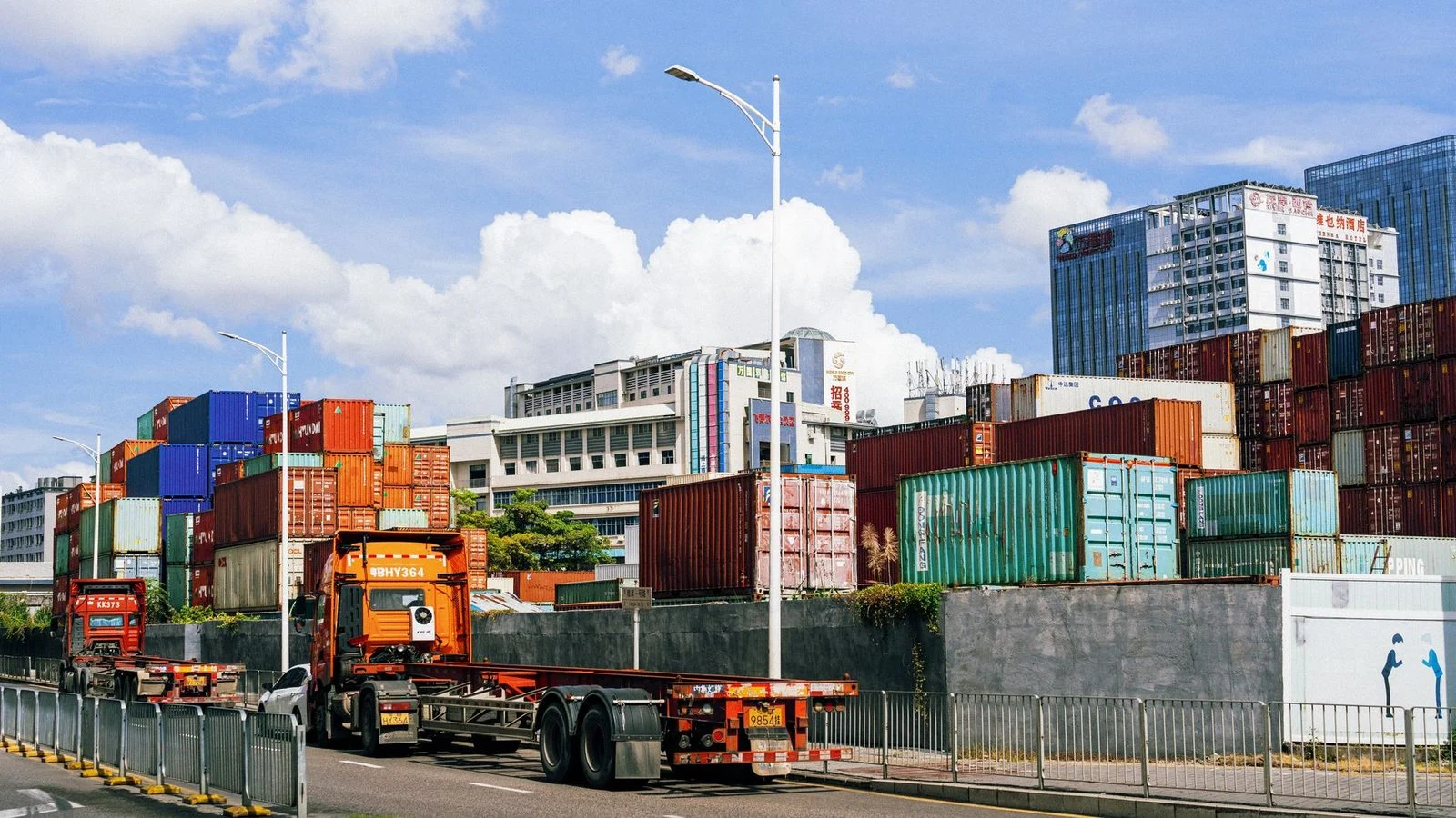 Stacked colorful shipping containers at an industrial port under a clear blue sky.