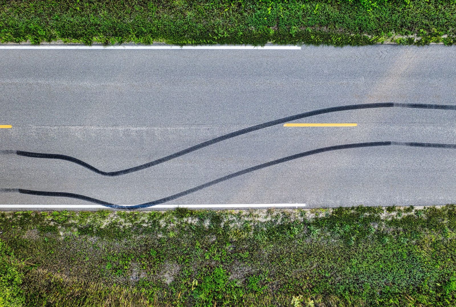 Vista aérea de marcas de frenado en una carretera rural con curvas.