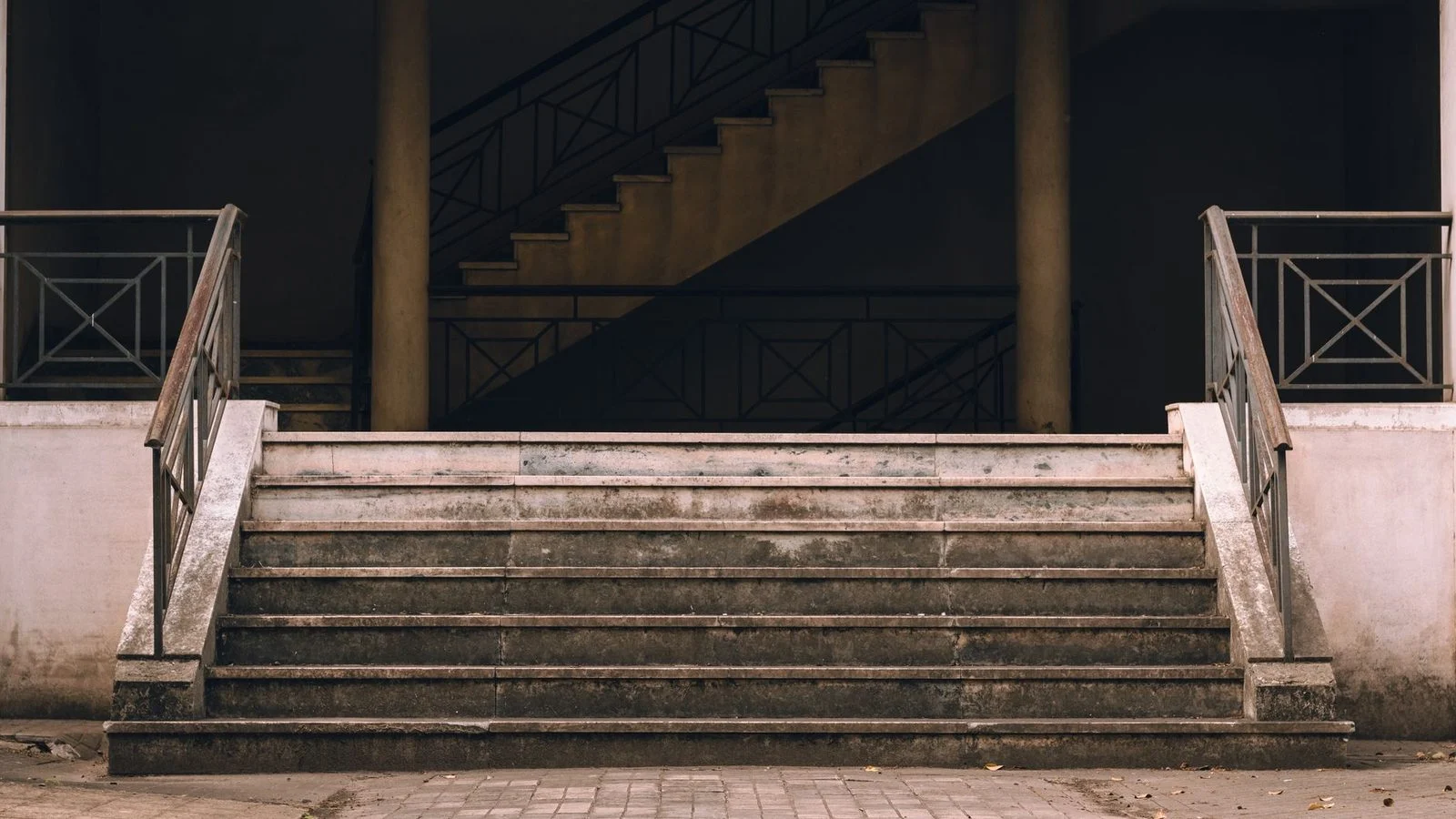 Weathered concrete stairs leading up to a building entrance on a city street in Rosario, Argentina.